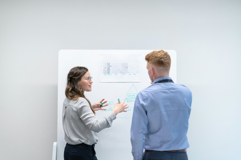 Zwei Personen besprechen sich im Büro an einem Whiteboard